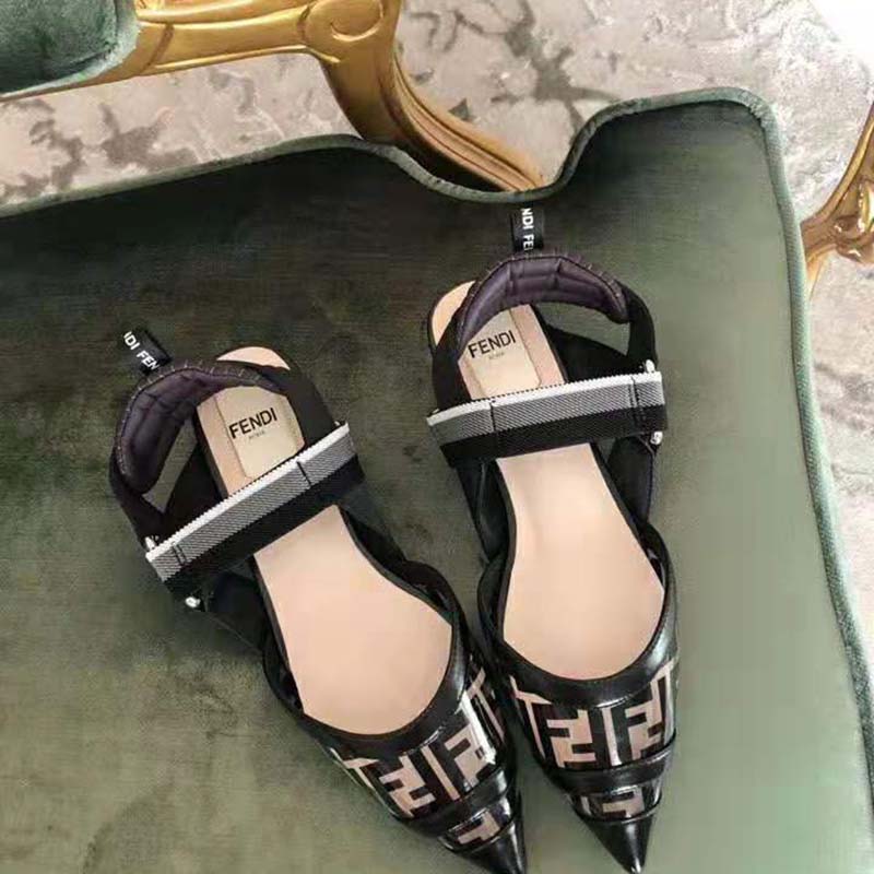 Close-up detail of Fendi logo hardware on black SABOTS flats