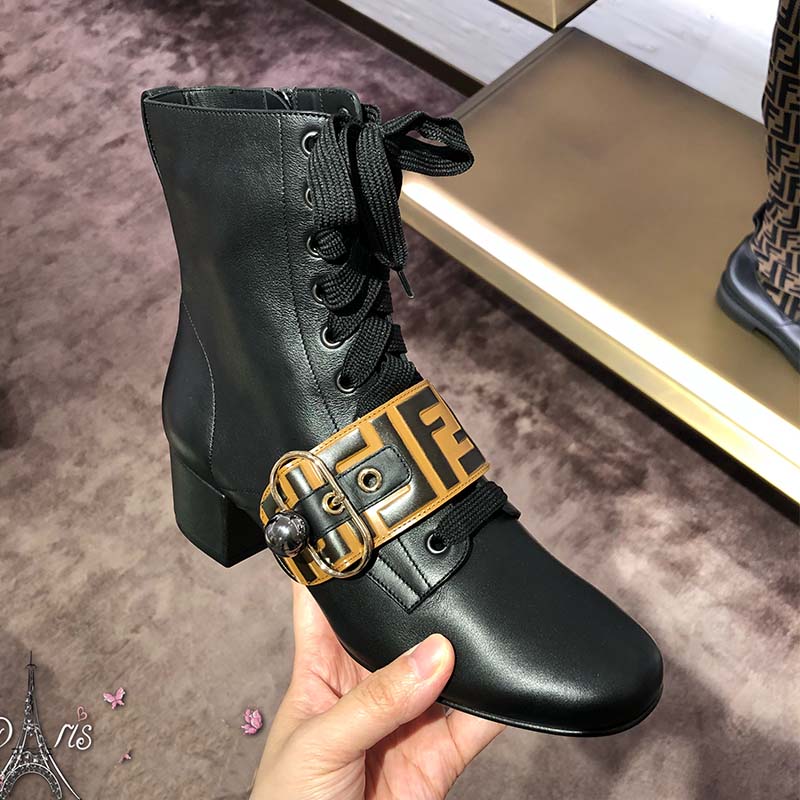 Close-up of gold Fendi logo hardware on black leather ankle boots