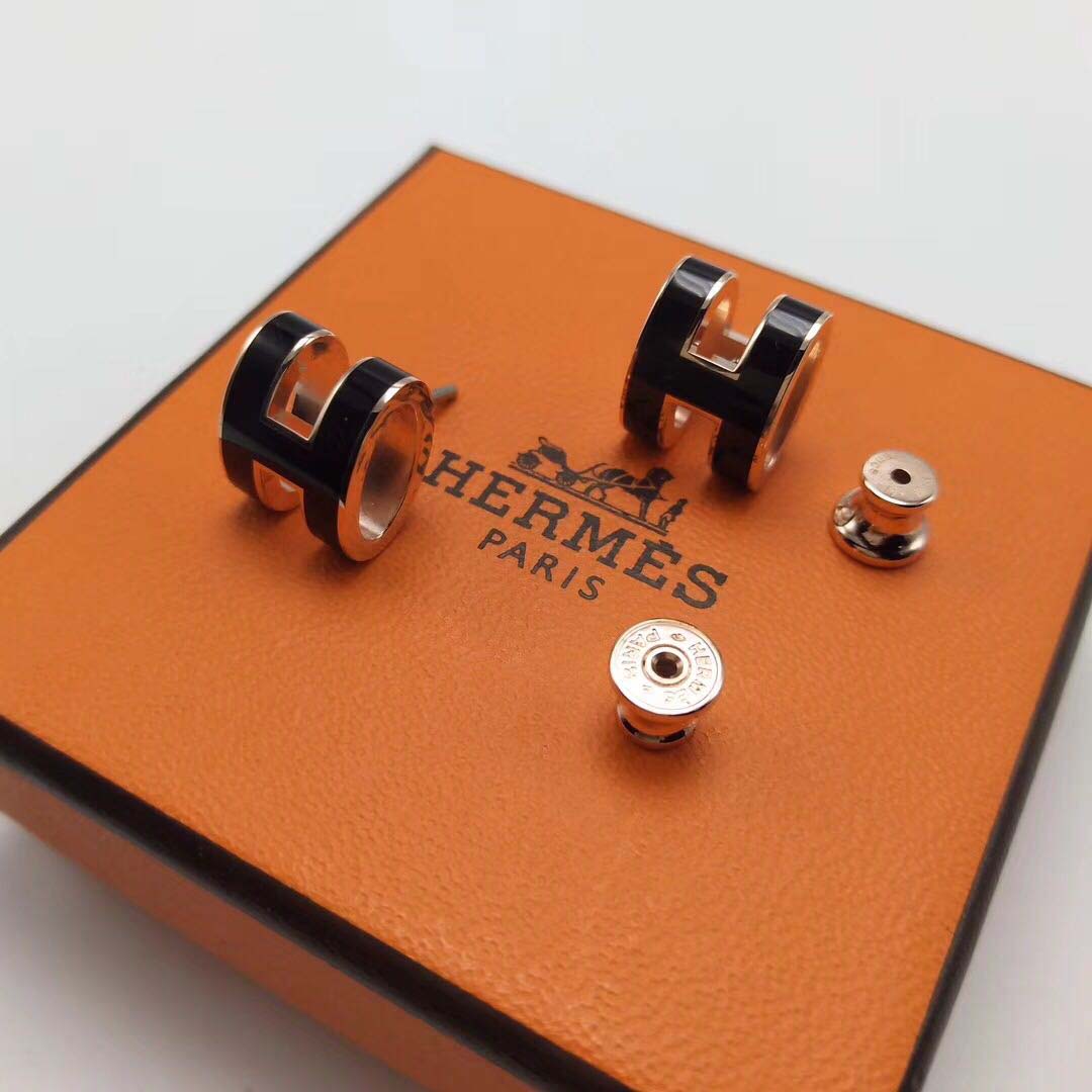 Close-up detail of black resin and Hermes H logo on earrings