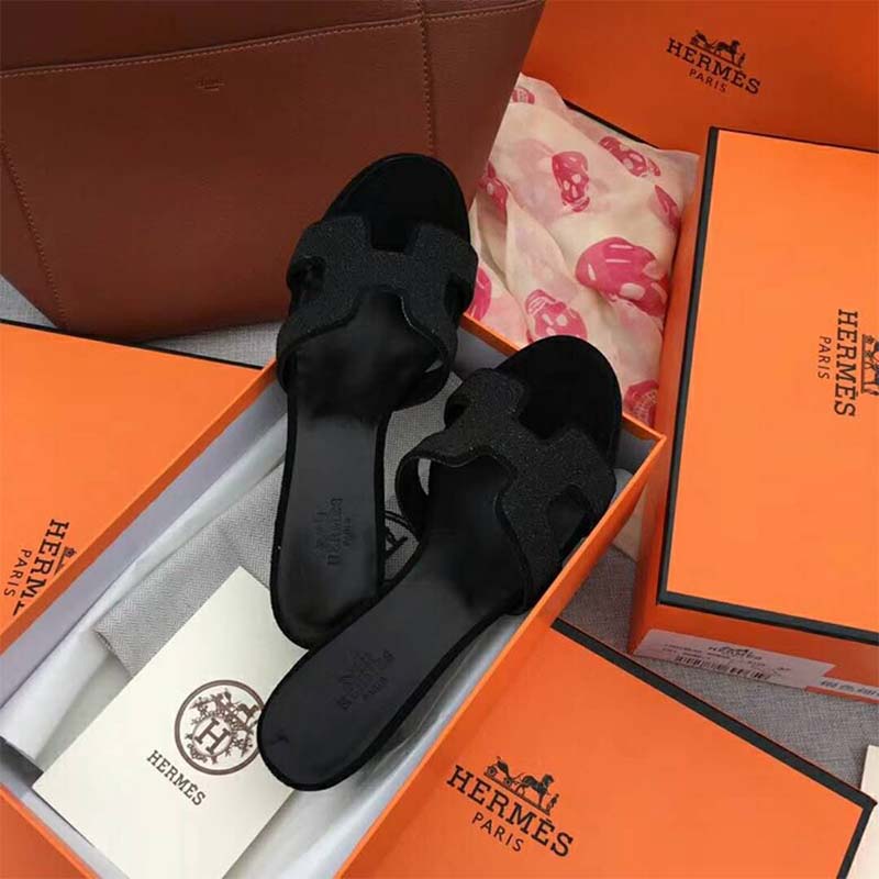 Close-up on black leather and signature Hermes ‘H’ cutout detail on sandal