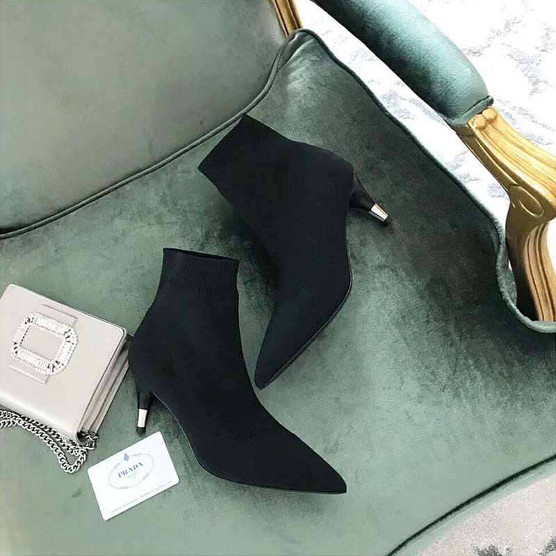Close-up detail of Prada logo hardware on black fabric booties