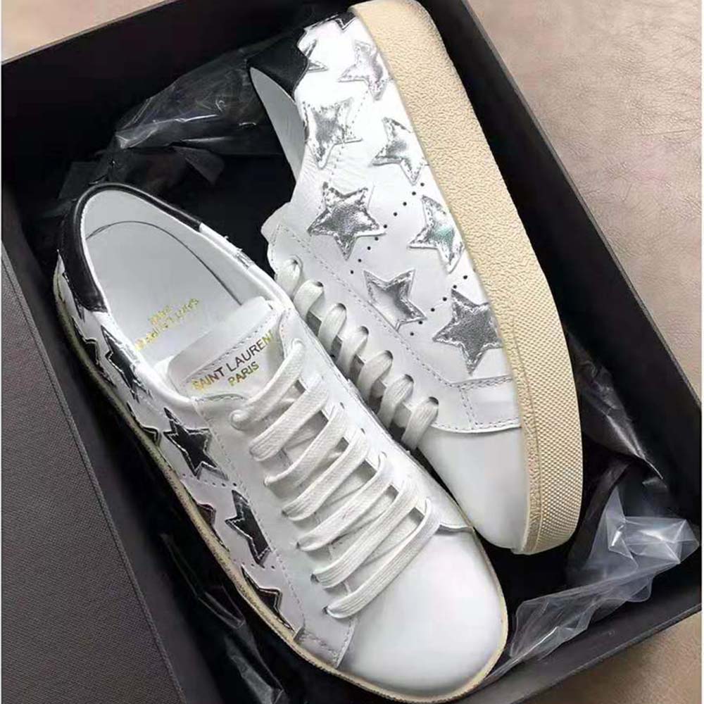 Close-up on metallic YSL logo detail on white leather sneaker