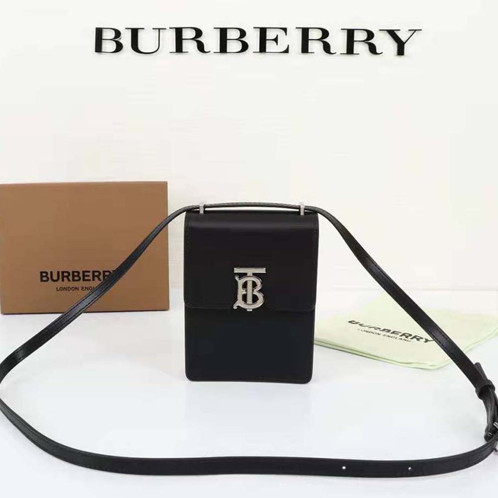 Close-up of Burberry Robin emblem and gold hardware on black leather