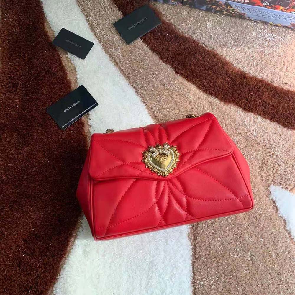 Close-up of gold devotion heart hardware on Dolce Gabbana D&G red shoulder bag