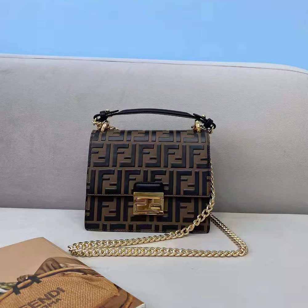 Close-up of gold-tone Kan U logo hardware on brown leather mini-bag
