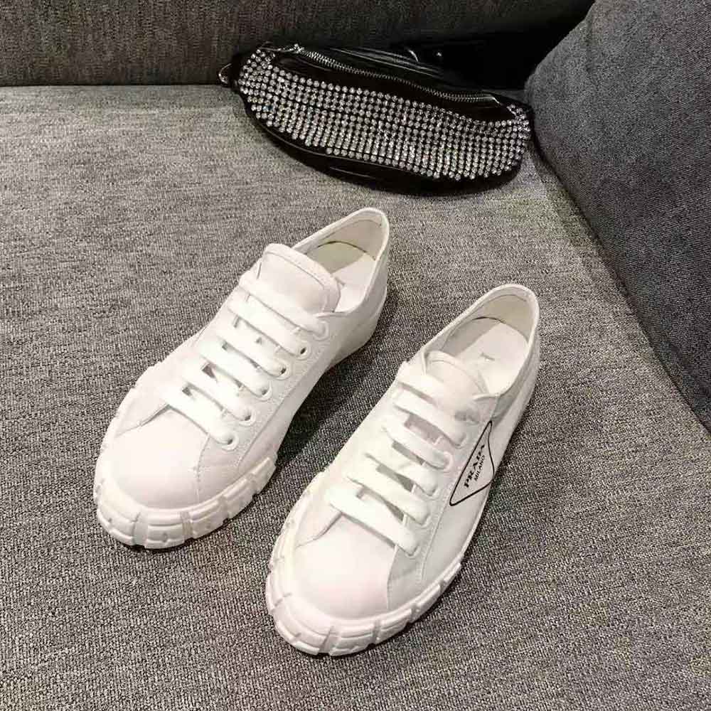 Close-up of white gabardine fabric and Prada logo detail on sneakers
