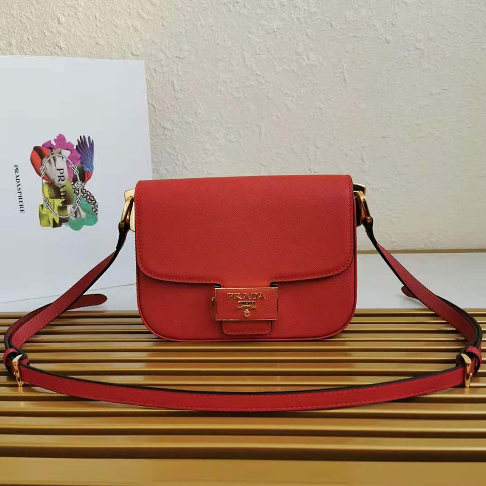 Close-up of gold-tone Prada emblem on red saffiano leather bag