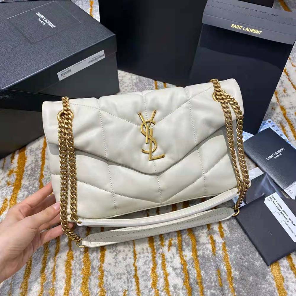 Close-up of gold YSL logo hardware on white quilted lambskin bag