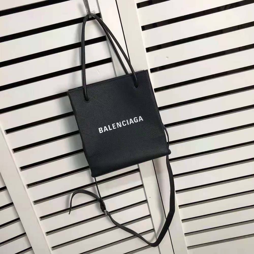 Side angle showing compact XXS silhouette of Balenciaga black tote bag