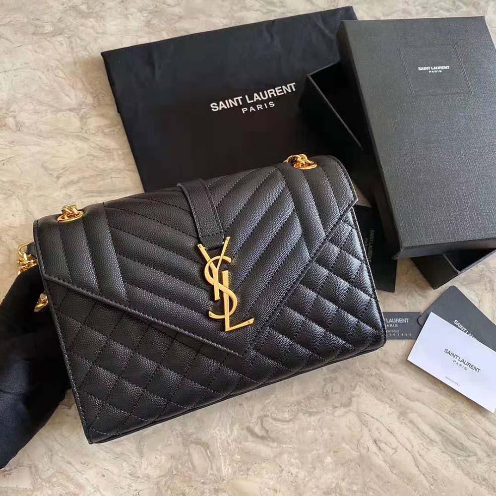Close-up of gold-tone YSL logo on black embossed leather bag