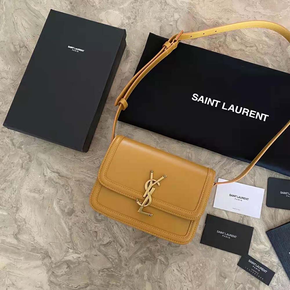 Close-up of gold YSL logo and clasp on yellow small satchel