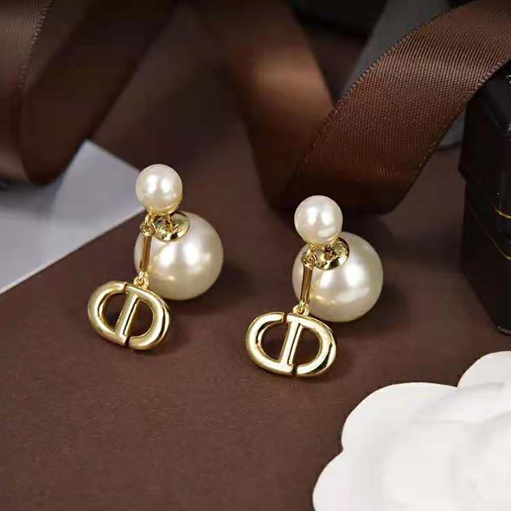 Close-up on white resin pearls and gold-finish metal earrings detail