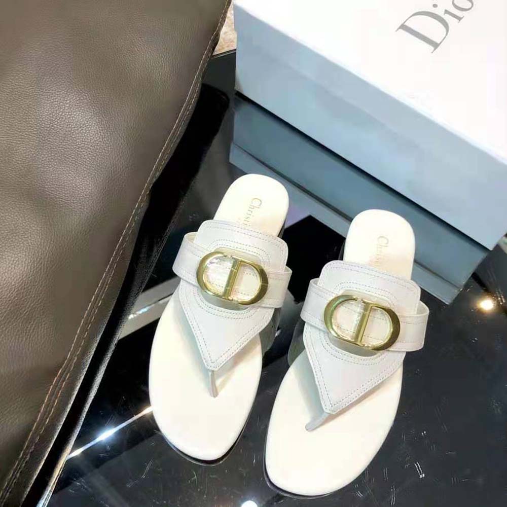 Close-up of metal Dior 30 Montaigne detail on white calfskin sandal