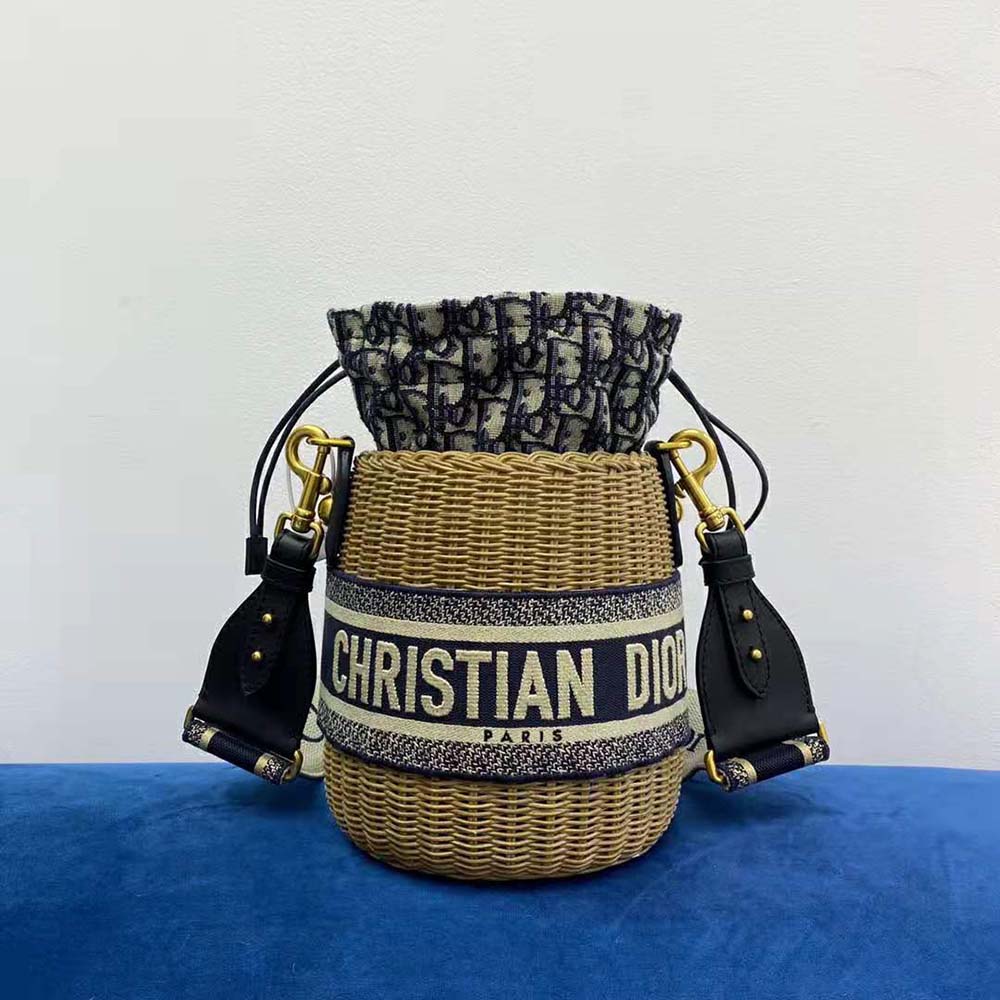 Side angle showing silver hardware and drawstring closure of Dior wicker bucket bag