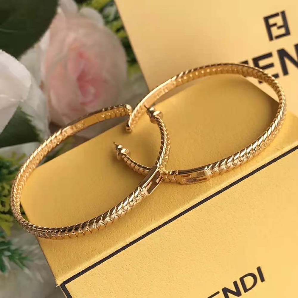 Close-up detail of signature Fendi logo on gold baguette earrings