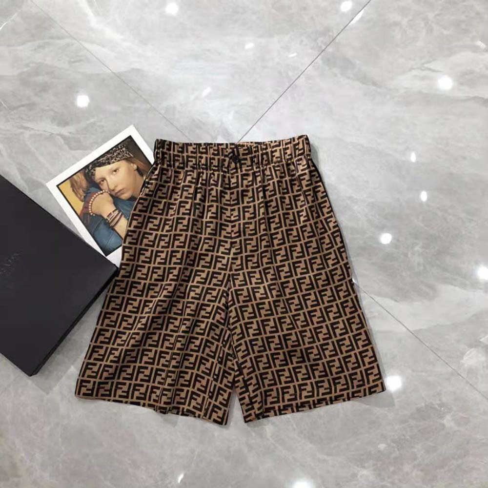 Close-up on branded button and textured brown twill fabric of Fendi bermudas