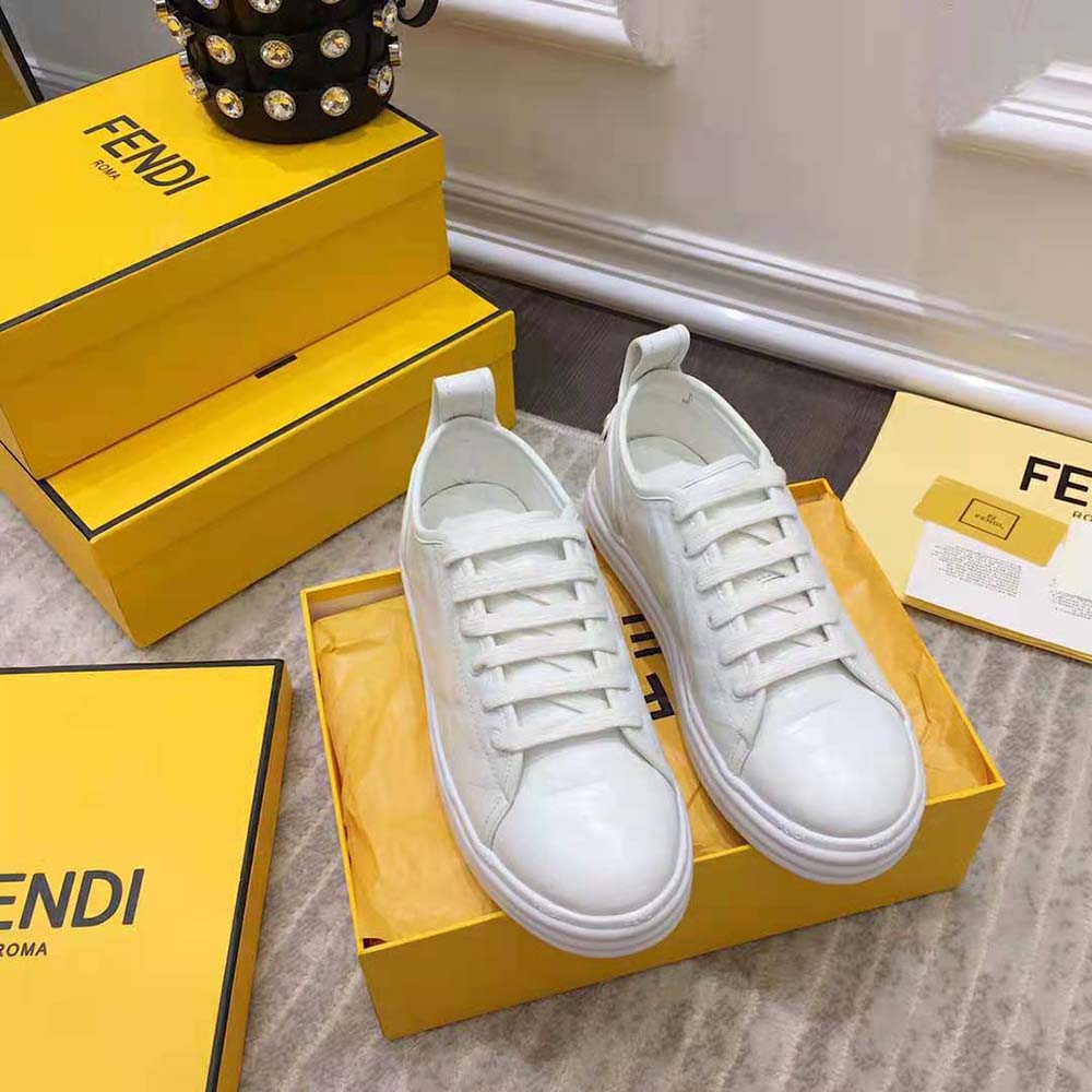Close-up on embossed Fendi logo hardware on white leather sneaker
