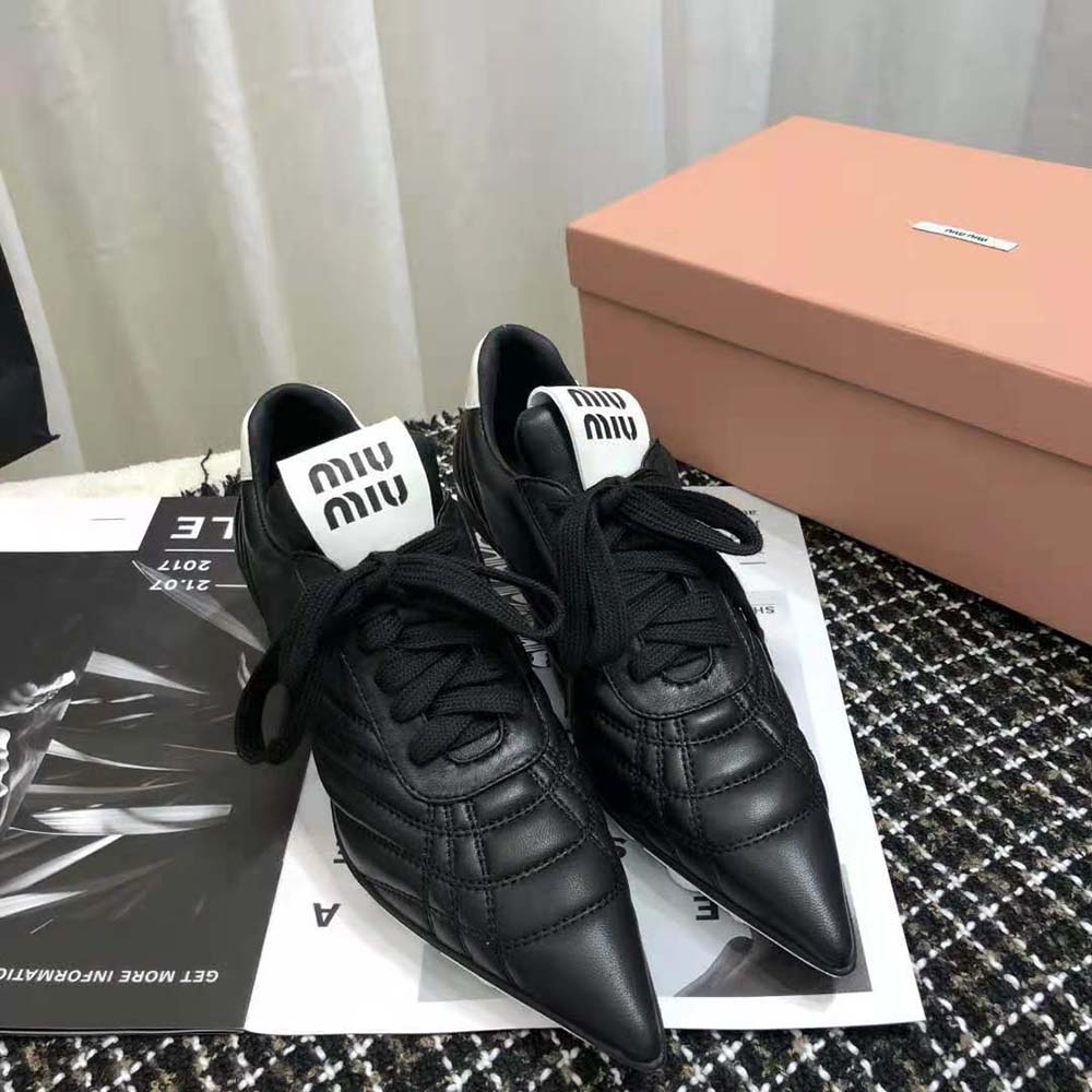 Close-up detail of black nappa leather and signature hardware on Miu Miu sneakers