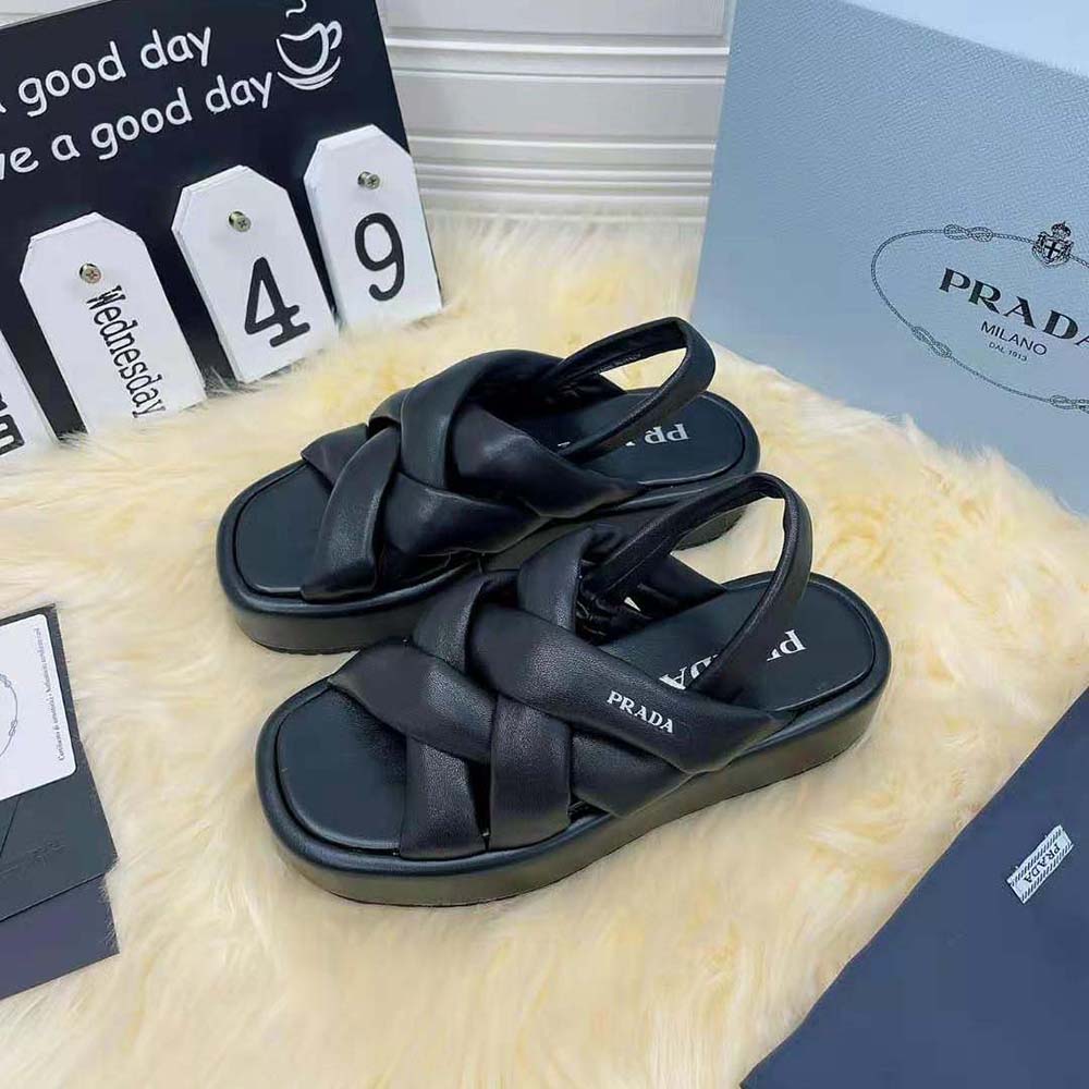 Close-up of black nappa leather and Prada embossed buckle detail on sandals