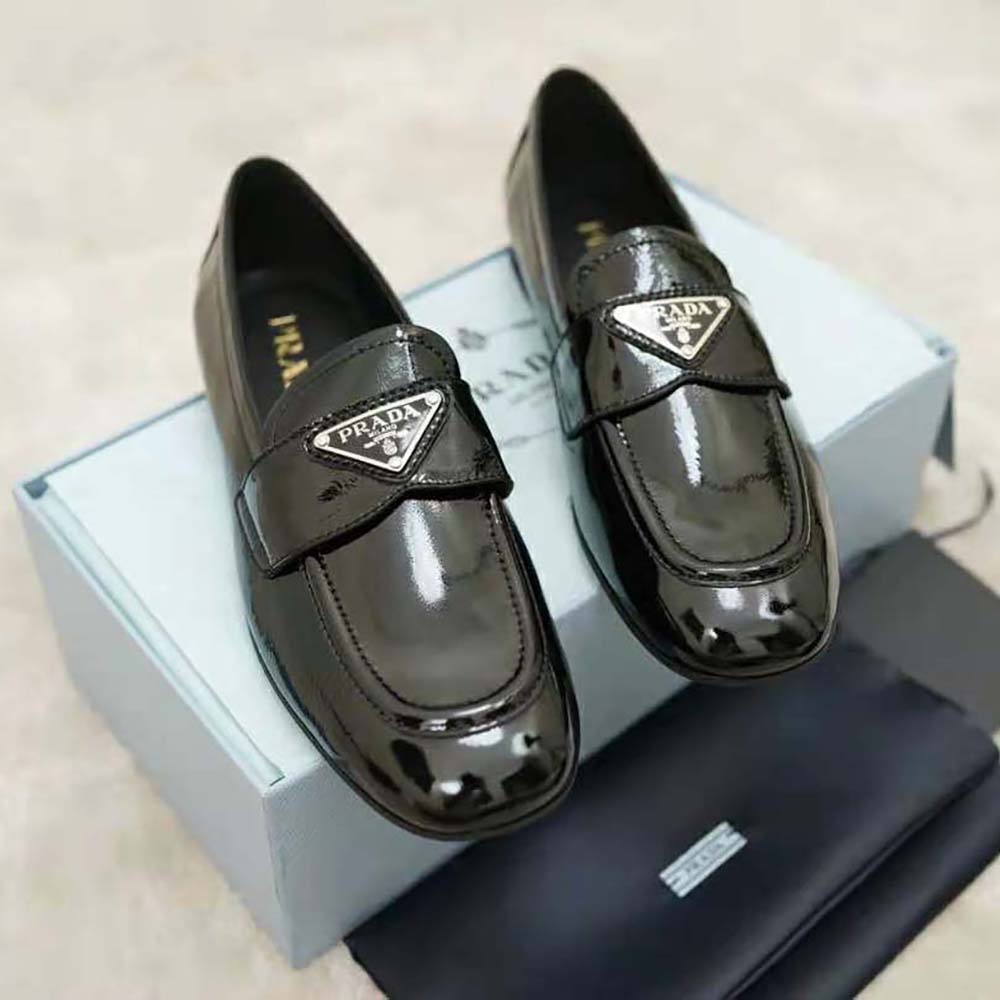 Close-up detail of patent leather and Prada logo on black loafers