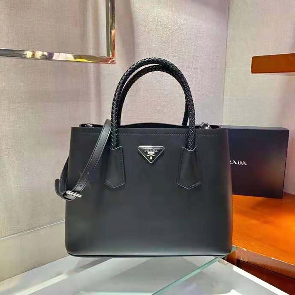 Close-up of silver Prada logo hardware on black leather handbag