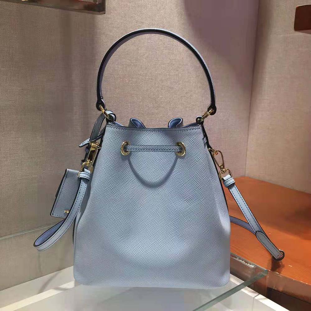 Side angle showing bucket silhouette and adjustable strap of Prada Women Saffiano Leather Bucket Bag-Blue