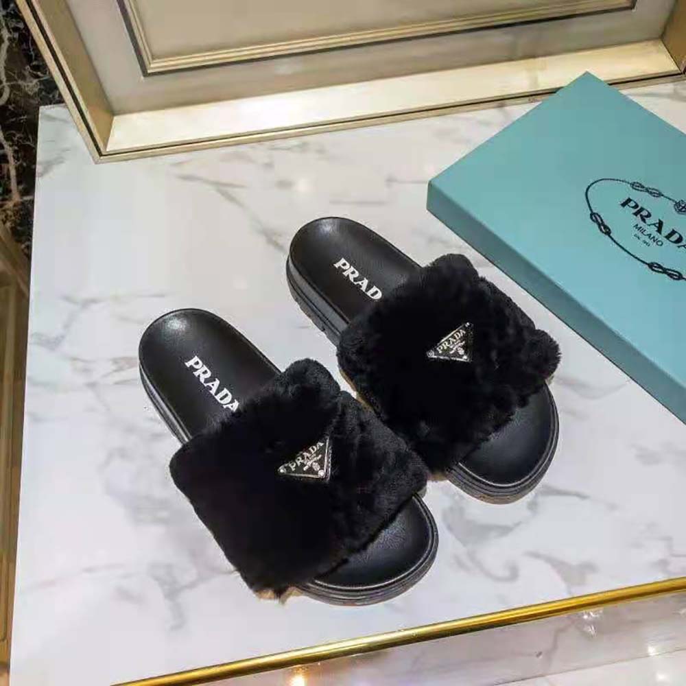 Close-up of Prada embossed strap on black shearling slides