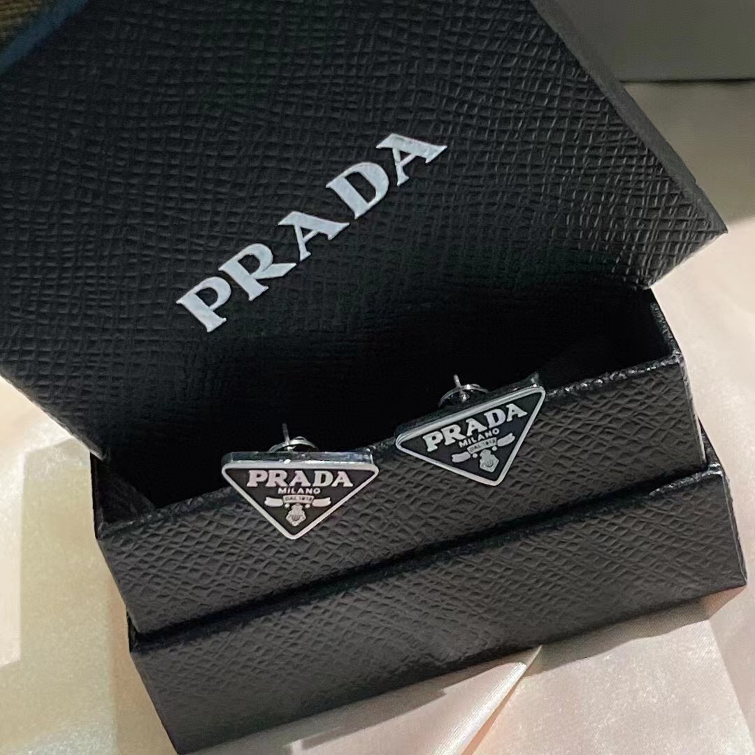 Close-up detail of gold-tone Prada logo on black earring