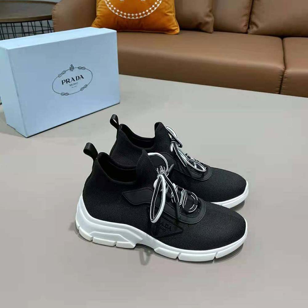 Close-up of black knit fabric and Prada triangle logo on sneakers
