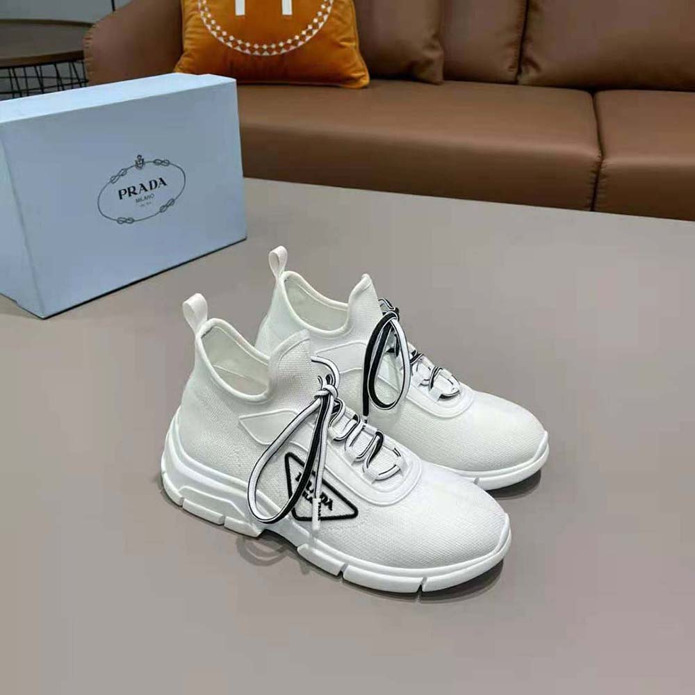 Close-up of signature Prada triangle logo on white knit sneakers