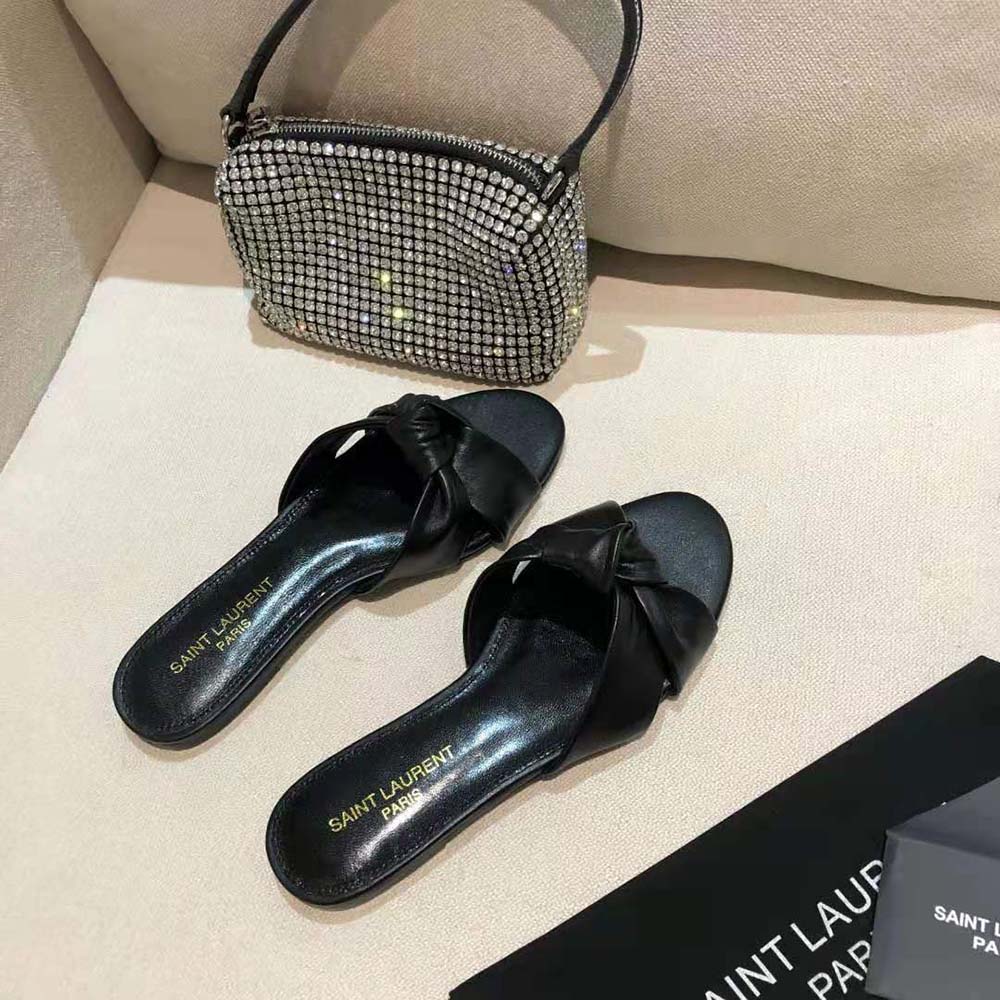 Close-up on gold YSL logo hardware of Bianca Flat Mules black leather