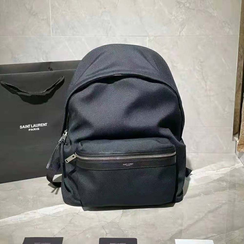 Close-up of gold YSL logo on black canvas mini backpack