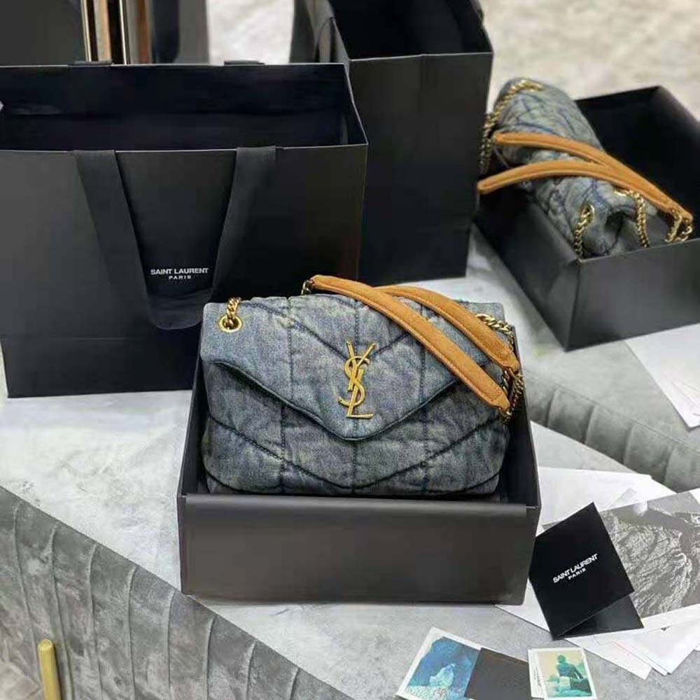 Close-up of gold YSL logo and suede trim on the Saint Laurent YSL puffer bag