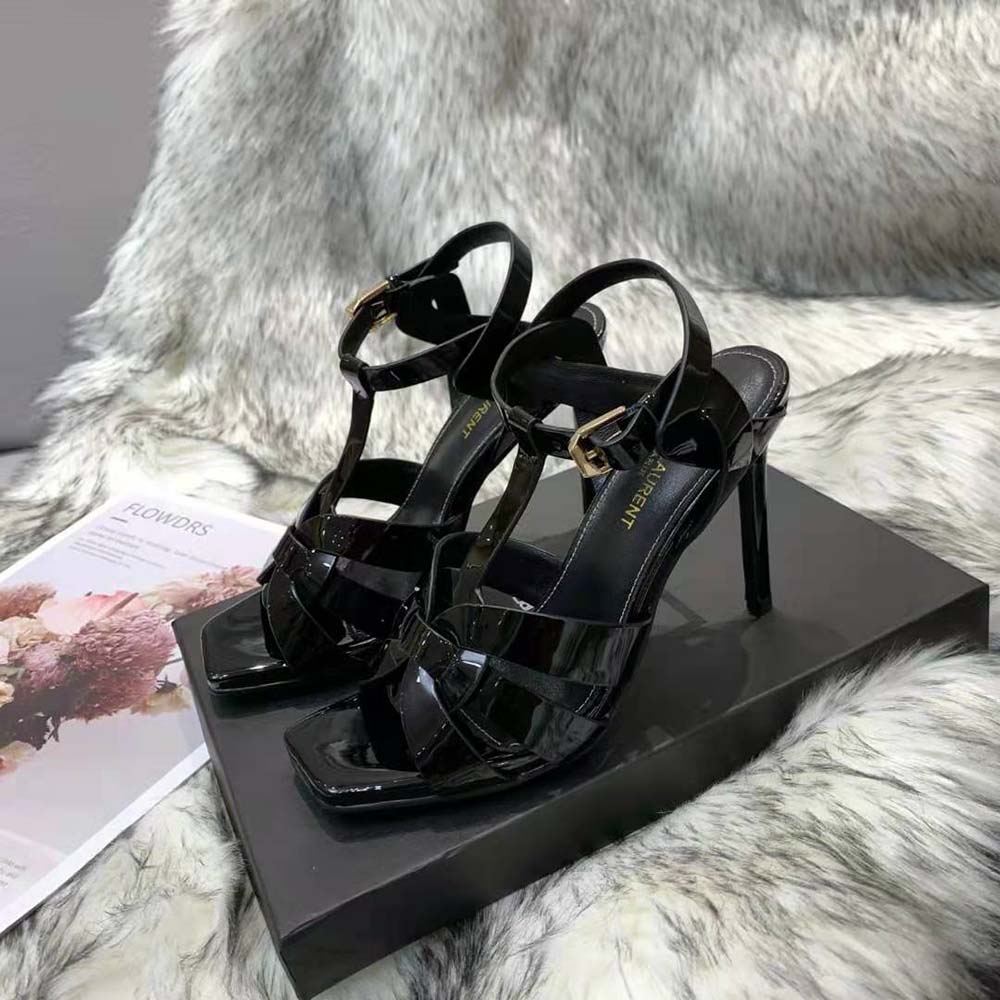 Close-up of YSL logo hardware on black patent leather Tribute Sandals