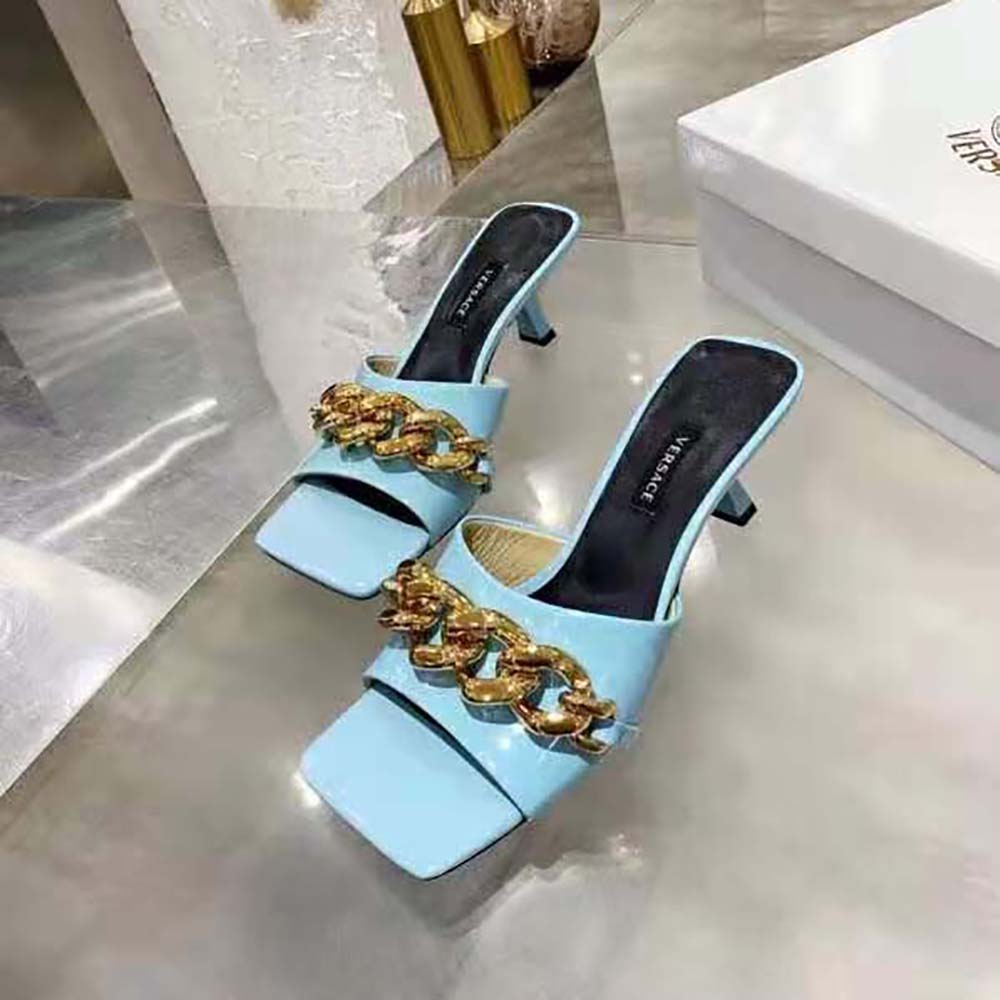 Close-up detail of gold Medusa chain on Versace blue mules