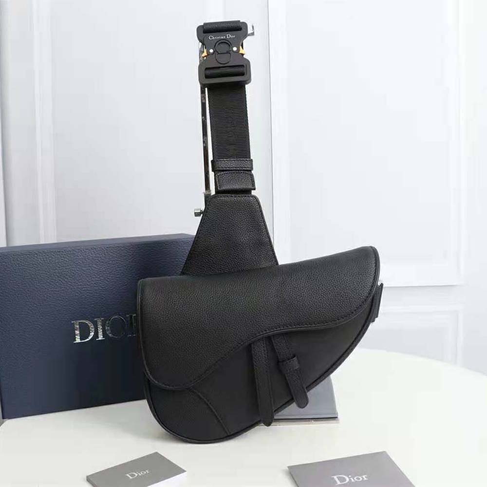 Close-up of antique gold 'D' charm on Dior Men Saddle Bag Black Grained Calfskin