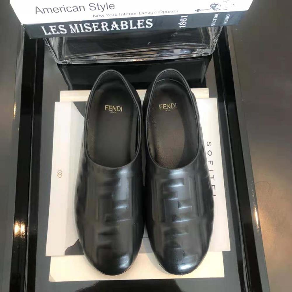 Close-up of embossed Fendi signature on black leather slippers