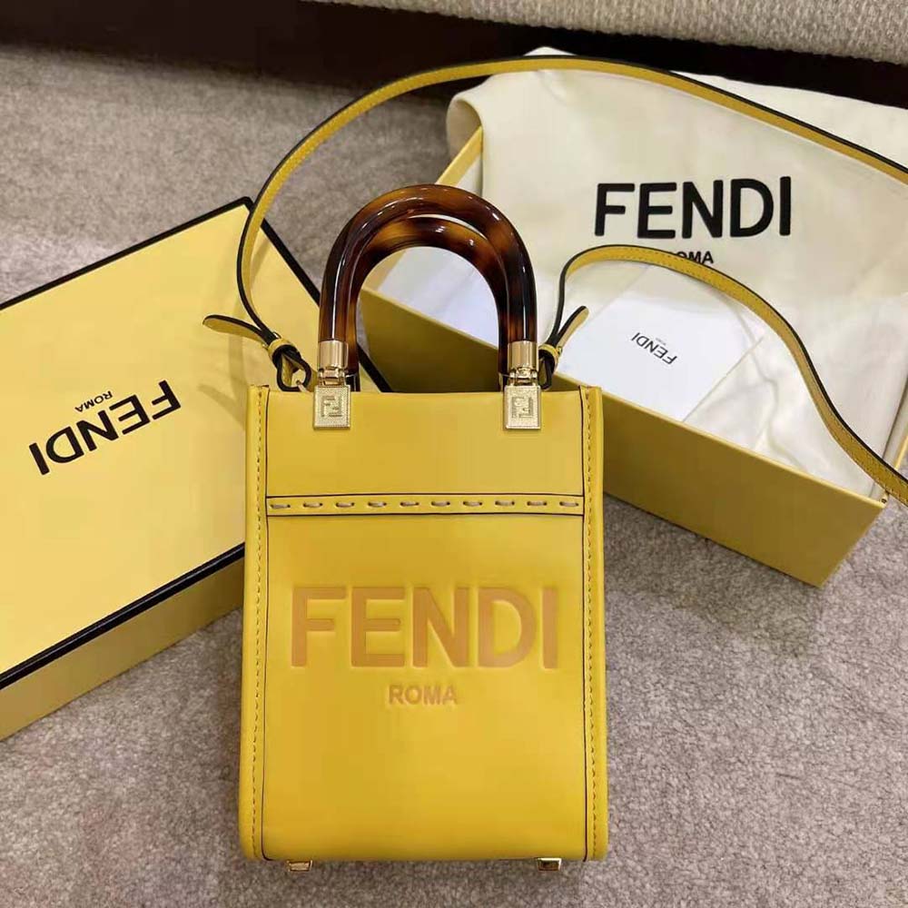 Close-up of gold-tone Fendi logo hardware on yellow leather mini-bag