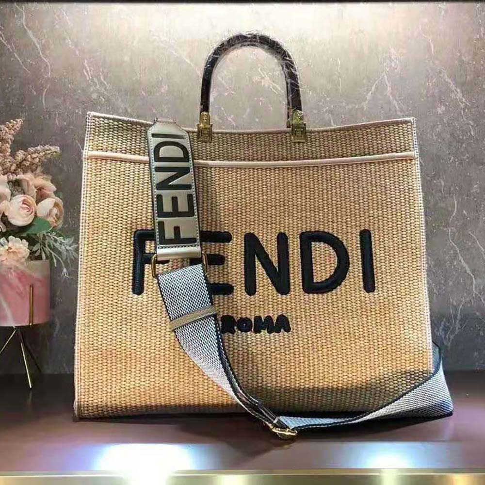 Close-up detail of Fendi gold-tone logo on woven straw shopper