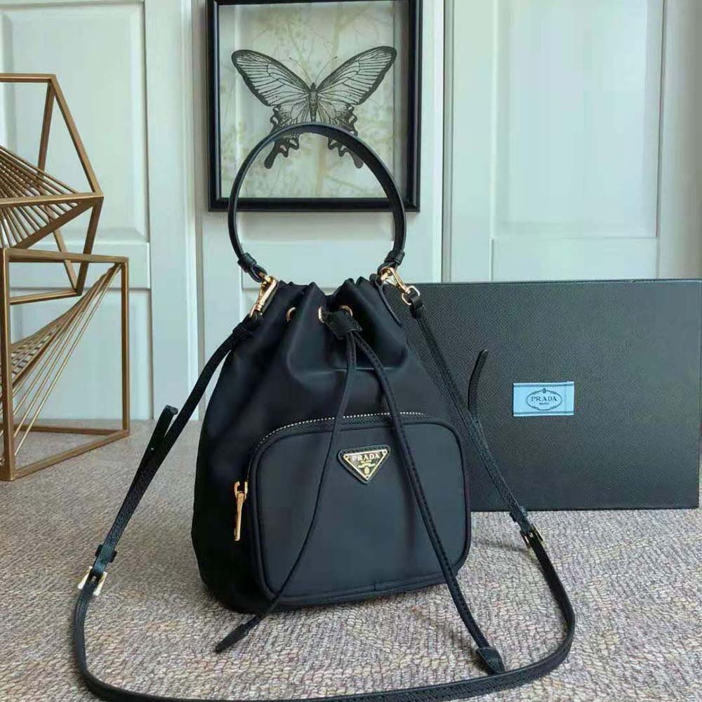 Close-up of gold-tone Prada logo plaque on black Duet Re-Nylon bag