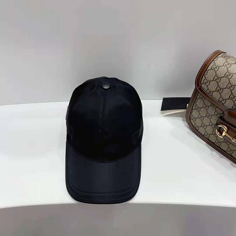 Close-up of Prada triangle metal logo on black Re-Nylon baseball cap