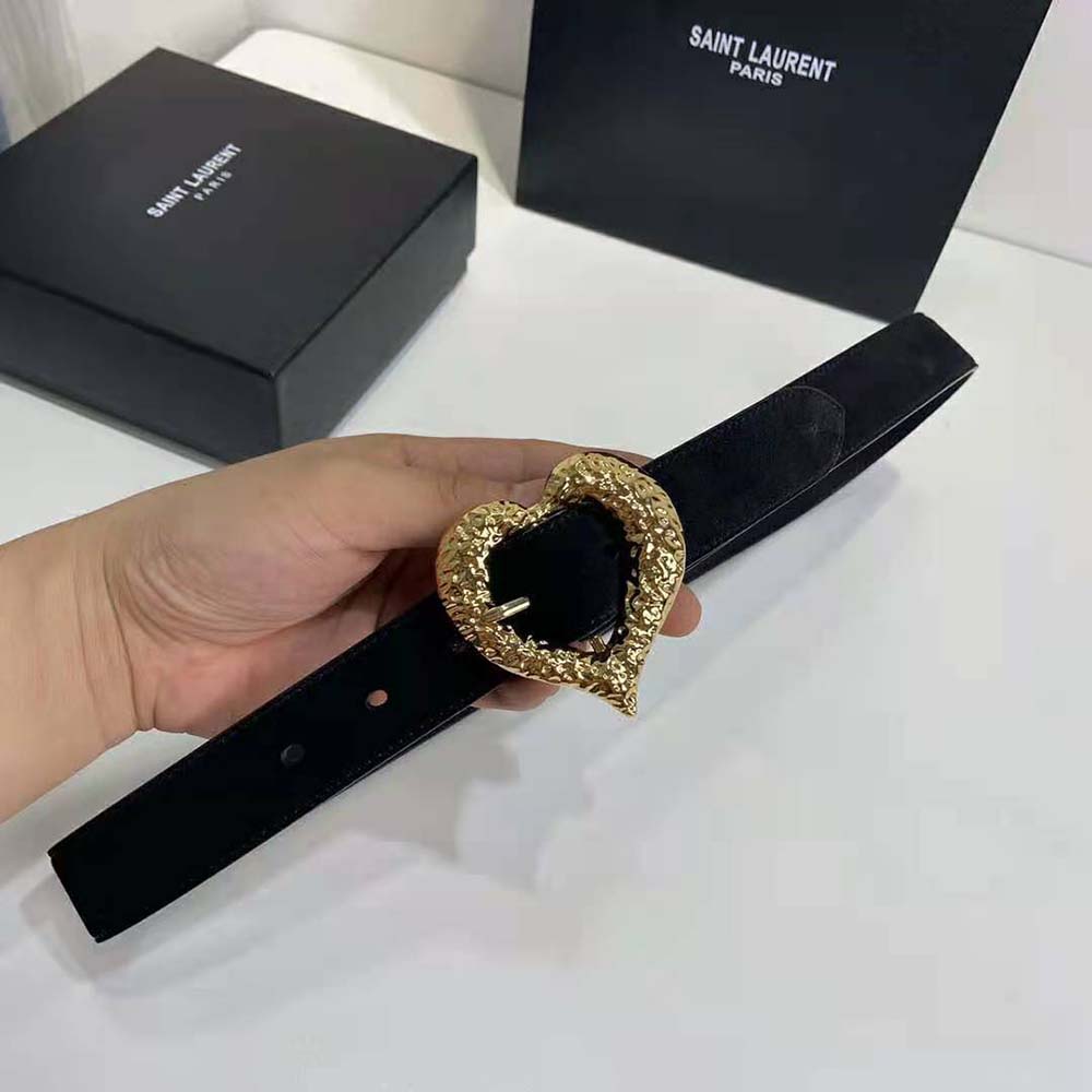 Close-up detail of gold heart-shaped YSL buckle on black lambskin belt