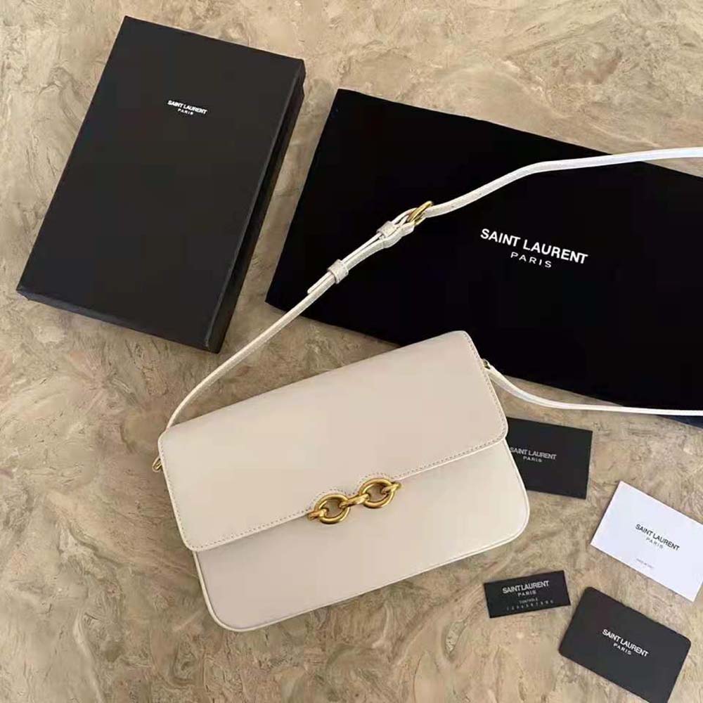 Close-up detail of YSL gold-tone chain hardware on white leather satchel