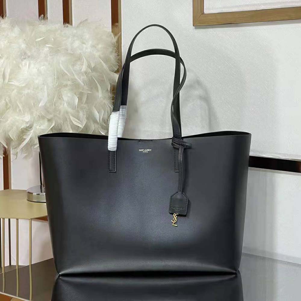 Close-up of gold YSL logo hardware on black leather shopping bag