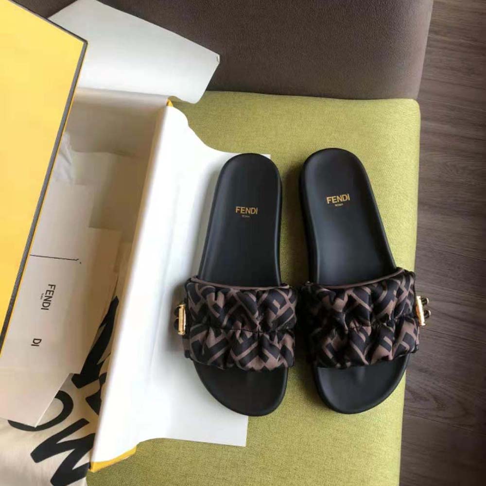 Close-up of gold Fendi logo hardware on brown satin slide
