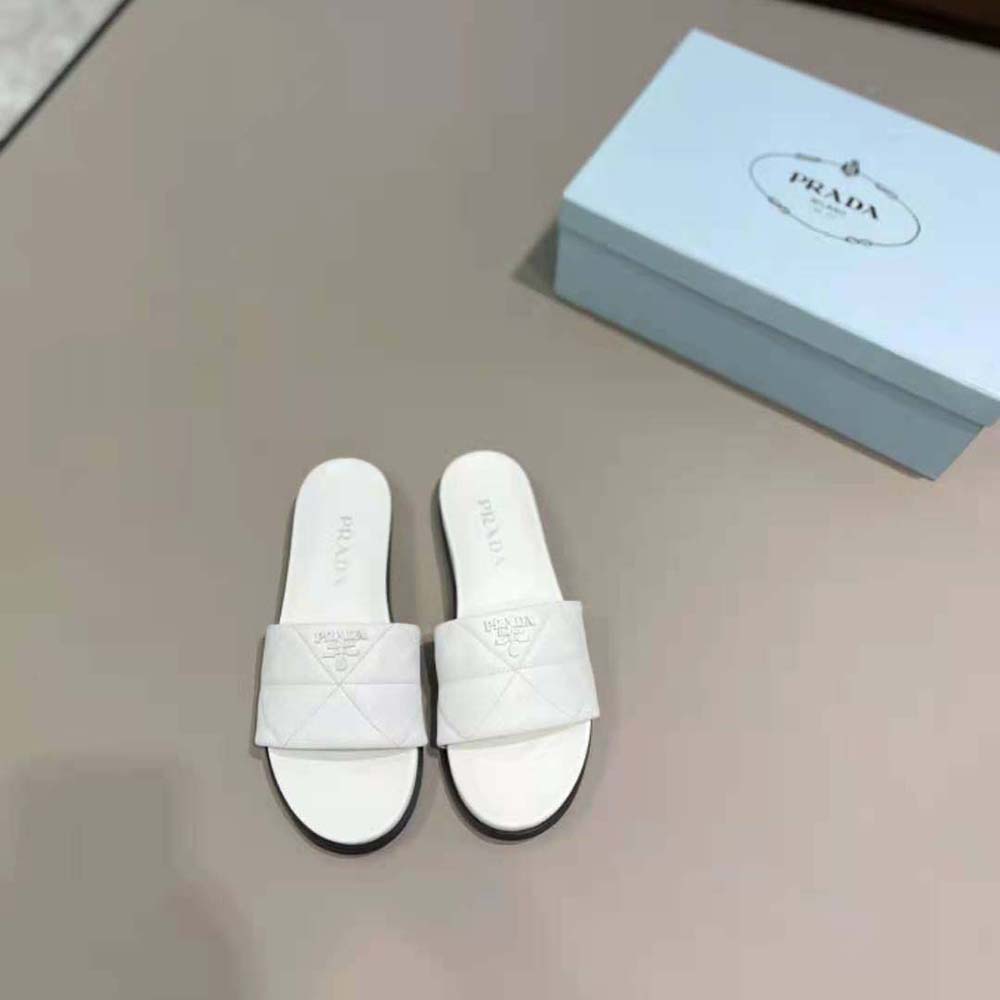 Close-up of smooth nappa leather and Prada logo on white slides