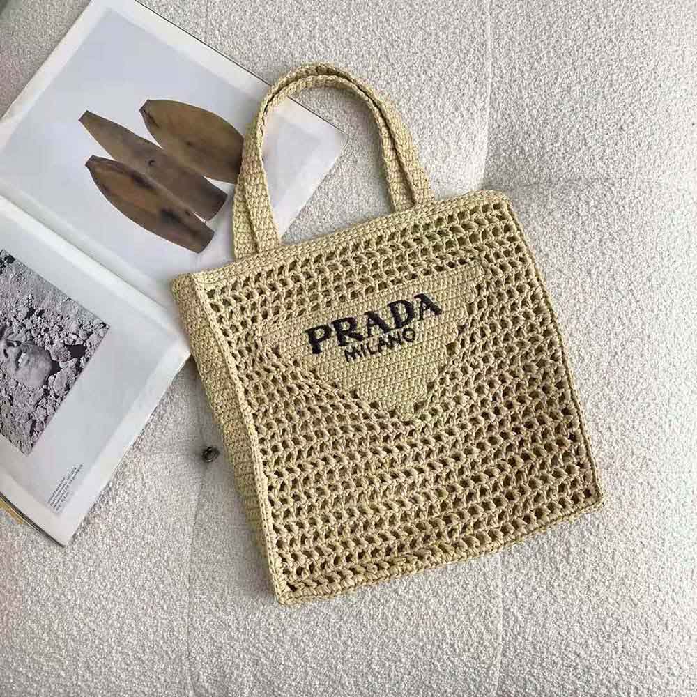 Close-up of gold-tone Prada logo on natural raffia tote