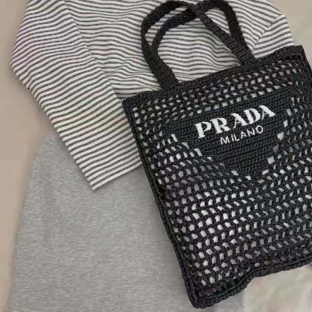 Close-up of gold Prada logo hardware on black raffia tote bag