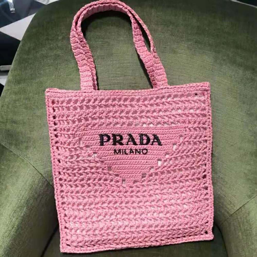 Close-up on silver-tone Prada logo and pink raffia texture