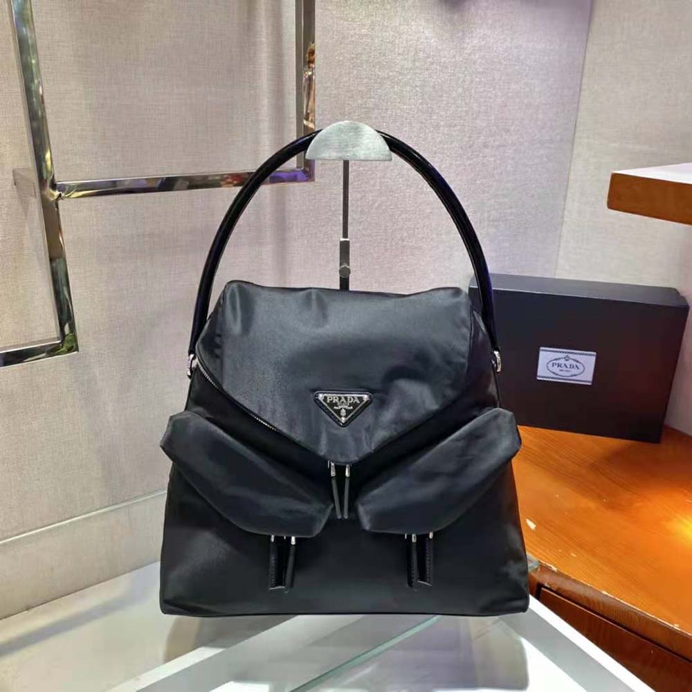 Close-up of Prada logo hardware on black nylon and leather bag